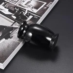 Close-up of a small 70x45mm glossy black aluminum pet cremation urn on dark surface.