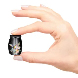Mini cremation urn for pet ashes with hummingbird floral pattern held by fingers