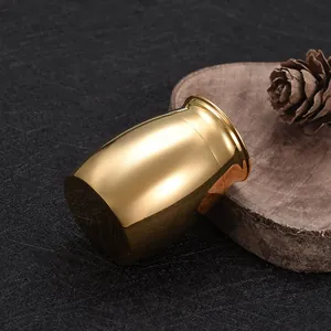 Miniature golden aluminum alloy pet cremation urn displayed on rustic wooden slice