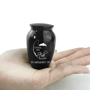 Piccola urna commemorativa nera con incisione da pesca tenuta in mano