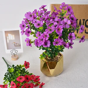 Künstliche violette Veilchenblüten mit Eukalyptusblättern in einem goldenen Topf.