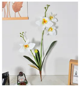 Detailed view of artificial white Cattleya orchid with four heads and green leaves