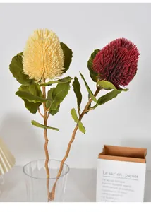 Realistic artificial yellow and red Banksia flowers in a modern glass vase for home decor