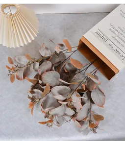 Detailed close-up of artificial eucalyptus branches with berries in warm earthy autumn tones.