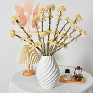 Tallos de bayas de arroz artificiales en un jarrón blanco para la decoración de mesa