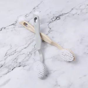 Pair of dual-headed long handle shoe brushes with soft white bristles on marble surface