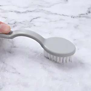 Grey long-handle soft bristle cleaning brush for shoes shown on a marble surface