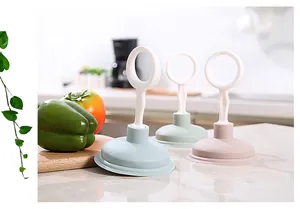 Three colorful kitchen sink plungers for drain cleaning shown in a kitchen setting