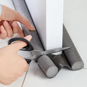 Flexible grey twin door draft stopper being trimmed to fit a white door bottom seal.