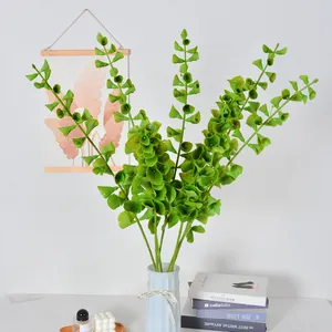 Kunstmatige groene eucalyptusbladeren in een lichtblauwe vaas voor interieurdecoratie