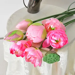 Elegante künstliche rosa Lotusblumen mit Knospen und grünem Pod auf weißem Tisch