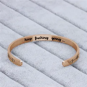 Détail d'un élégant bracelet jonc en or rose avec le message gravé keep fucking going