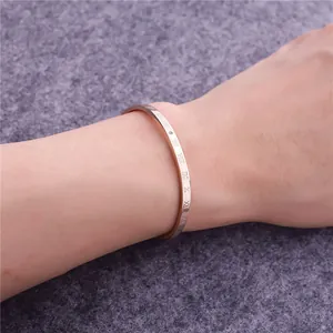 Detail eines roségoldenen Armreifs mit römischen Ziffern und einem kleinen Diamanten