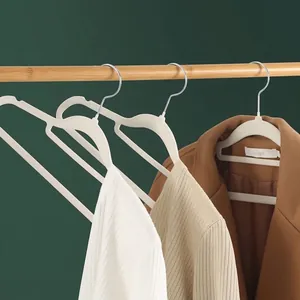 Non-slip ivory velvet flocked clothes hangers on a wooden rod with sweaters.