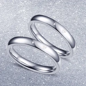 Nahaufnahme von Titanstahl-Pärchenringen mit feiner Herzgravur und einem kleinen Diamanten.