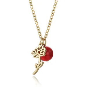 Macro view of gold-plated stainless steel hollow flower pendant with vibrant red bead