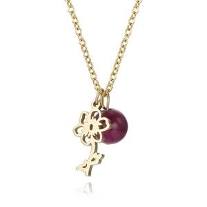 Detail of hollow gold flower pendant and purple bead on titanium steel chain necklace.