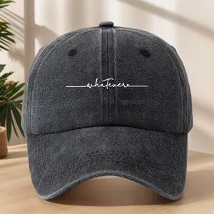 Dettaglio cappello baseball in denim lavato con ricamo bianco della scritta whatever