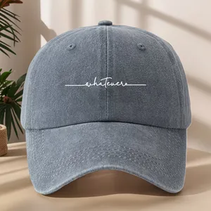 Dettaglio di un cappello da baseball in denim lavato con ricamo bianco whatever