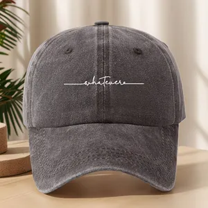 Primo piano di un berretto da baseball grigio vintage con scritta 'whatever'.