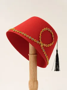 Detailed view of a red ethnic felt hat featuring gold trim with colorful gemstones
