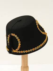 Detailed view of an ethnic black felt Fez hat with colorful gems and gold tassel.