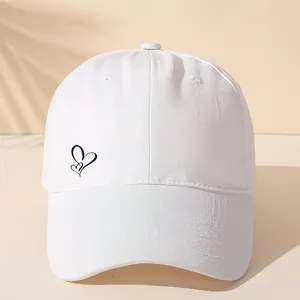 Detail der minimalistischen Herz-Stickerei auf einer weißen Baumwoll-Baseballkappe