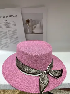 Close-up of pink flat-top straw hat with patterned paisley ribbon scarf