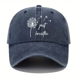 Detail of washed navy denim baseball cap featuring dandelion and 'just breathe' print