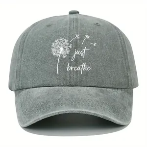 Close-up of artistic dandelion and 'just breathe' print on gray washed denim cap