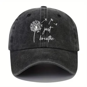 Detail showing a vintage washed denim baseball cap with dandelion print and 'just breathe' text