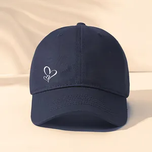 Nahaufnahme der dunkelblauen Baseballkappe mit einem weißen Herz-Stickerei-Detail.