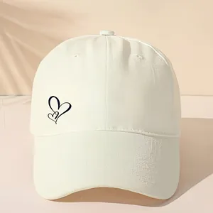 Detailansicht einer weißen Baseballkappe mit einem minimalistischen schwarzen Herz-Logo.