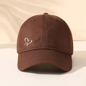 Detailansicht einer braunen Baseballkappe mit einem weißen gestickten Herzdesign.