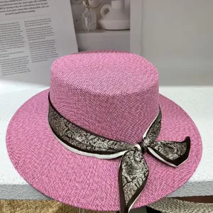 Elegant pink flat top straw hat with paisley ribbon for beach and vacation sun protection.