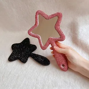 Detailansicht eines pinkfarbenen, mit Strass besetzten Handspiegels in Sternform für Make-up