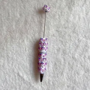 Detailed view of white beaded ballpoint pen featuring purple butterfly decorations