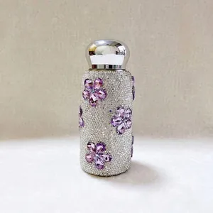 Nahaufnahme einer funkelnden, mit Strass besetzten Taschen-Thermoskanne mit lila Blumen