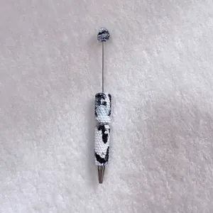 Detailed view of handmade ballpoint pen with black and white rhinestone cow print pattern
