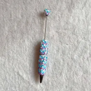 Detail of a decorative beadable pen with blue butterflies and pearls on plush fabric