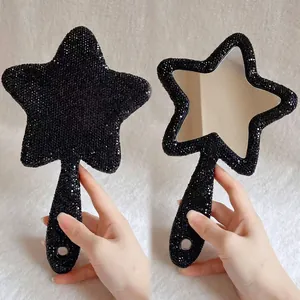 Detailansicht eines funkelnden handspiegels in sternform mit schwarzen strasssteinen