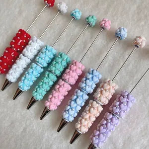 Detailed view of colorful beaded ballpoint pens with textured heart patterns and pearls
