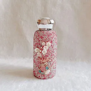 Detaillierte Makroansicht einer rosa strassbesetzten Isolierflasche mit 3D-Blumenelementen