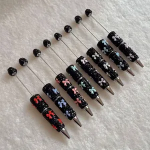 Detailed view of luxury sparkly rhinestone ballpoint pens with colorful clay bows on white fur