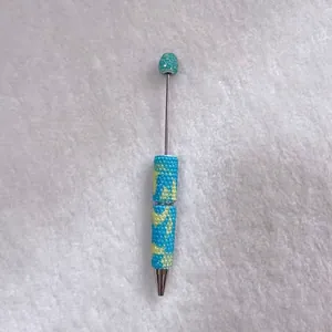 Close-up detail of candy-colored rhinestone ballpoint pen with blue and yellow patterns