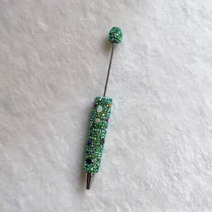 Detailed view of a handmade green rhinestone beaded pen with colorful stone accents.