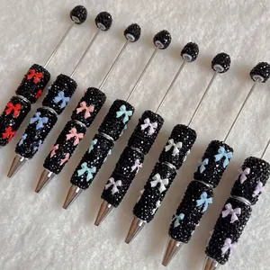 Detailed view of rhinestone-encrusted beaded pens with colorful polymer clay bow accents