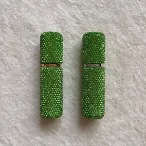 Close-up of two green rhinestone-encrusted 10ml portable perfume spray bottles