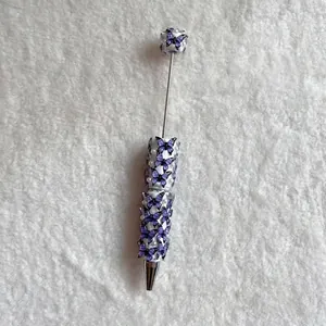 Detailed macro view of a handmade beaded ballpoint pen with purple butterflies and pearls.