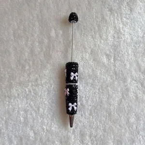 Luxury black rhinestone-encrusted ballpoint pen featuring elegant white bow accents